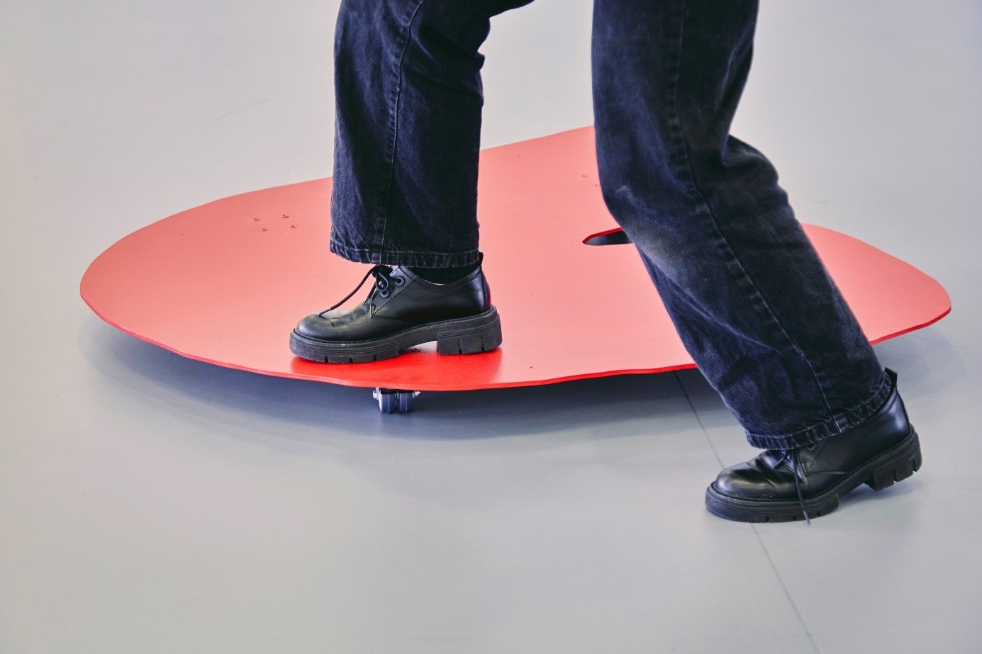 A man has one foot on a red rolling board