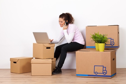 A woman sitting on moving boxes and talking on the phone