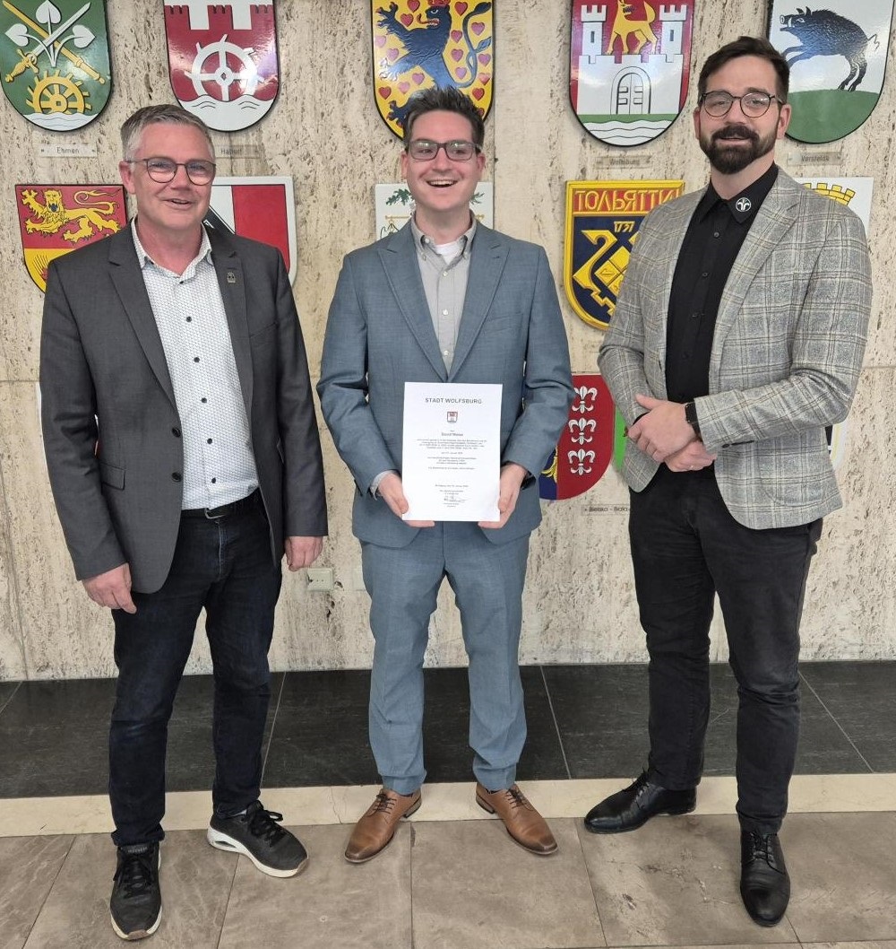᠎Pending Translation: Stadtrat Andreas Bauer (links) bei der Urkundenübergabe an David Weise mit Obermeister Christian Malak (rechts). Foto: Stadt Wolfsburg.