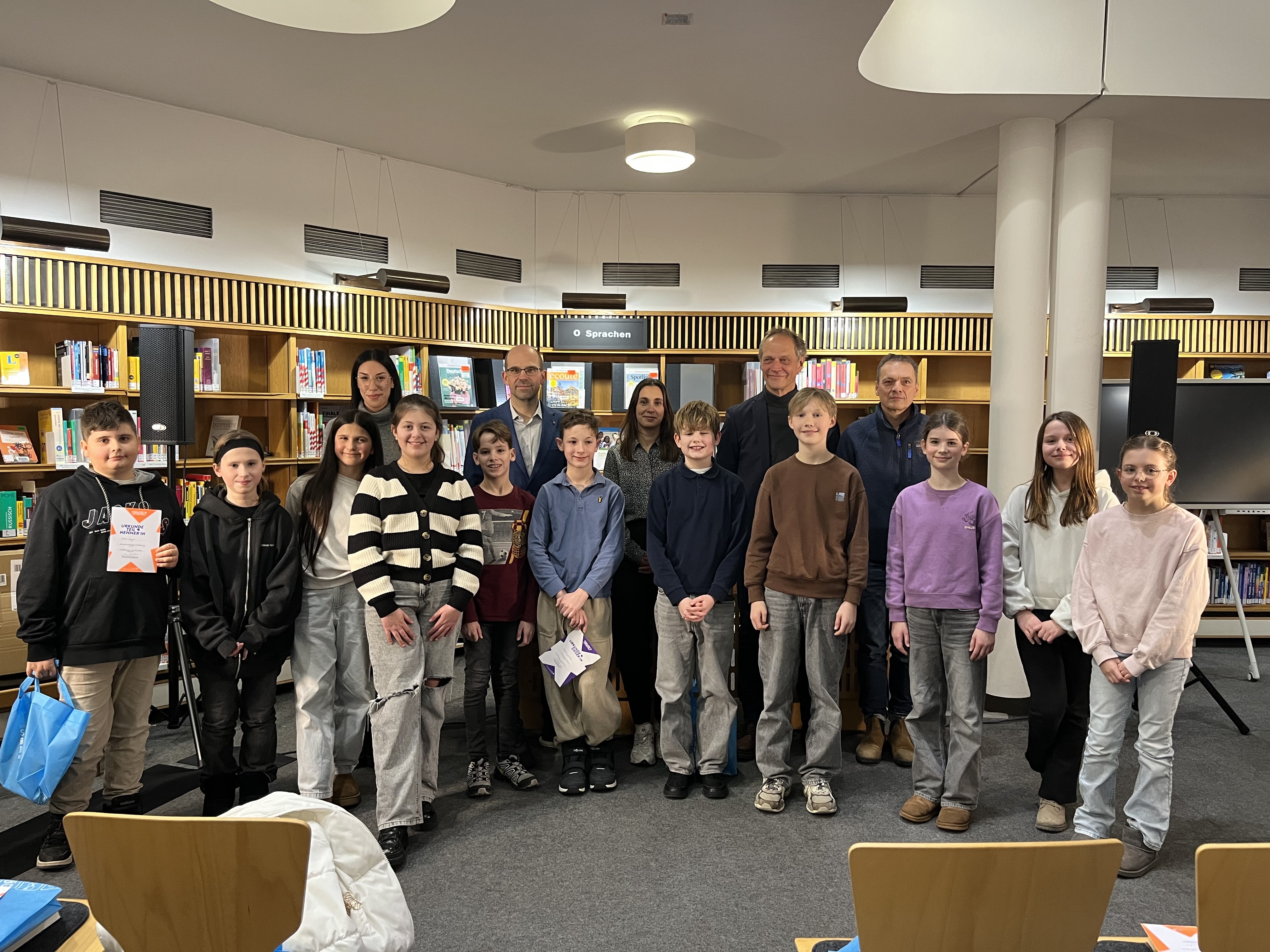 Bastian Scholz (vorne, mittig) mit Jury und weiteren Teilnehmer*innen des Vorlesewettbewerbs. Foto: Stadt Wolfsburg
