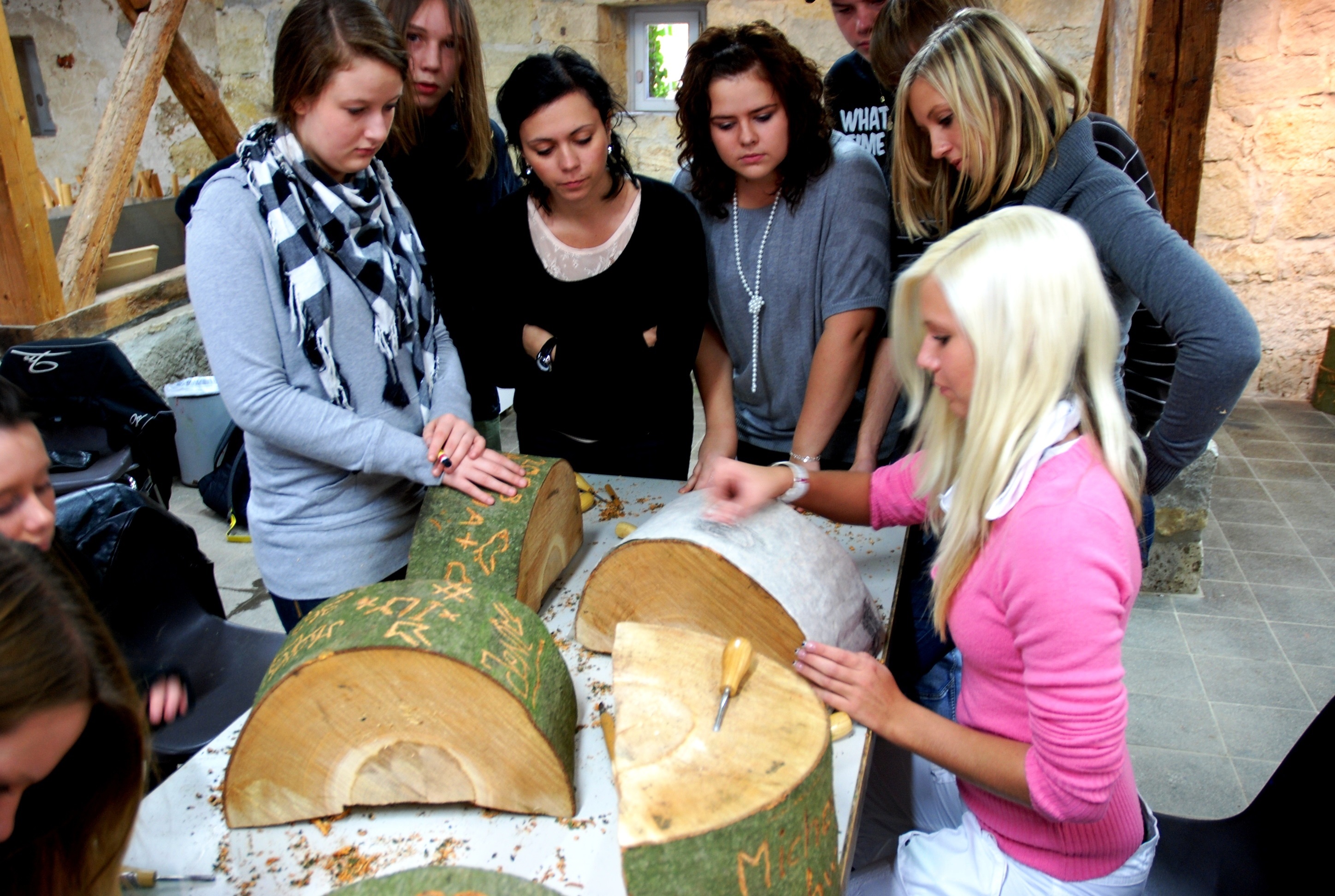 Mehrere Personen an einem Tisch mit Holzscheiben im Workshop Frottagen