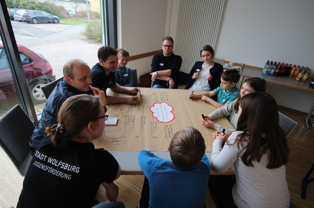 Kinder und Jugendliche sitzen an einem Tisch