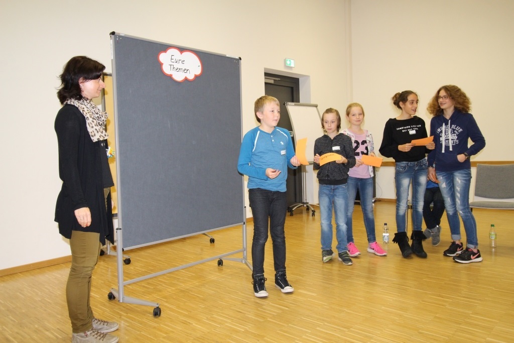 Kinder stehen bei einer Stellwand