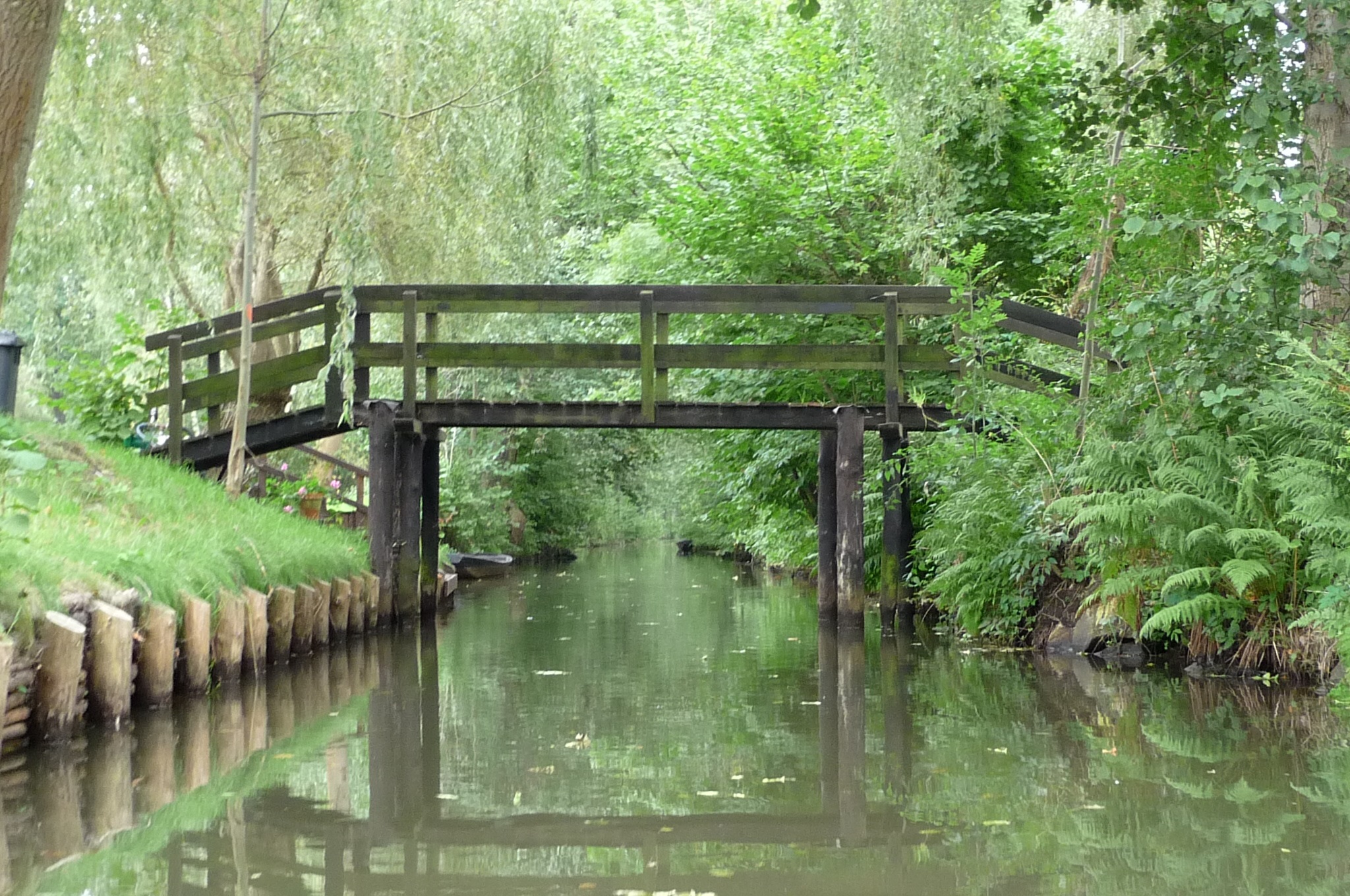 Ein ausgebautes Fließgewässer mit einer Holzbrücke