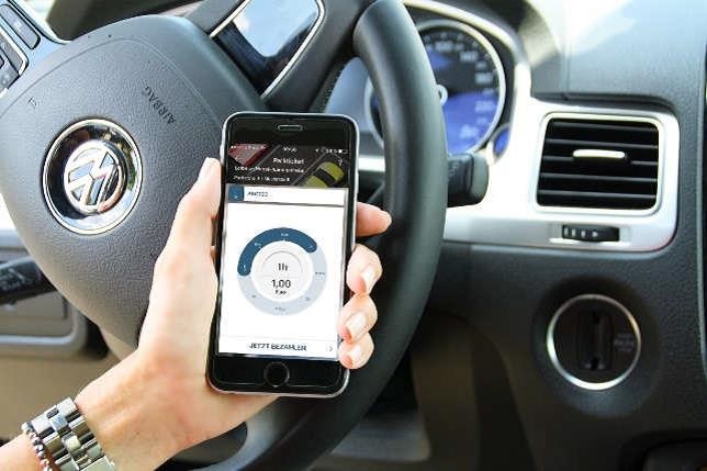 Eine Person bedient die App TraviPay in seinem Auto.