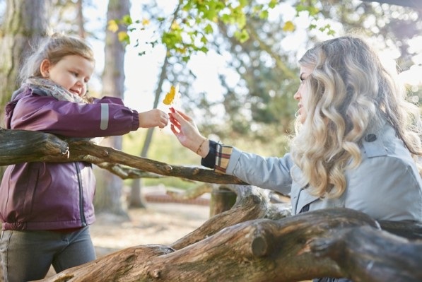 Eine Kindergärtnerin übergibt ein Blatt