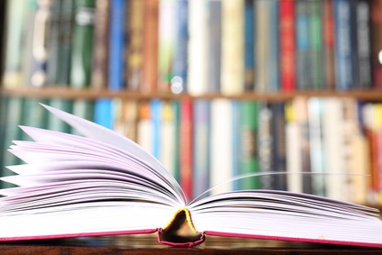 An open book in front of a wall of books