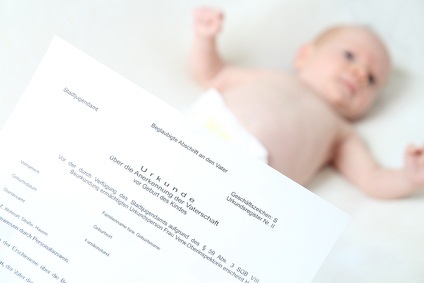 Vaterschaftsanerkennungsurkunde und Baby im Hintergrund