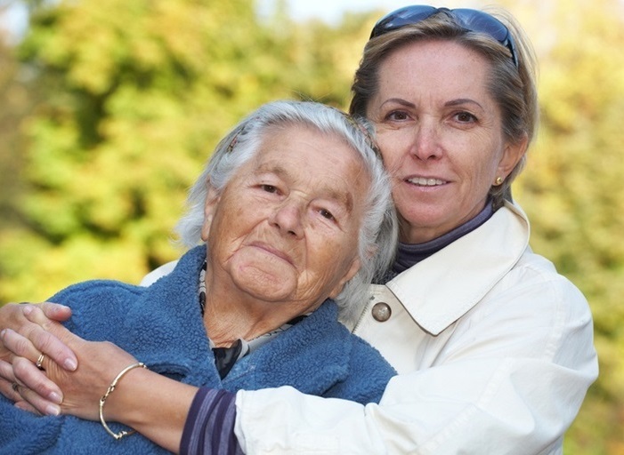 A young woman holds an old woman in her arms; Photo: absolut / Fotolia.com