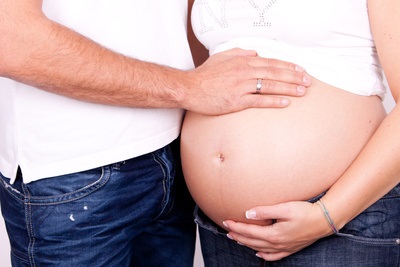 Ein Mann legt seine Hand auf den Bauch seiner schwangeren Frau
