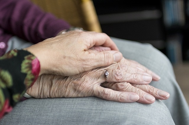 Eine Pflegerin legt ihr Hand auf die eine älteren Dame