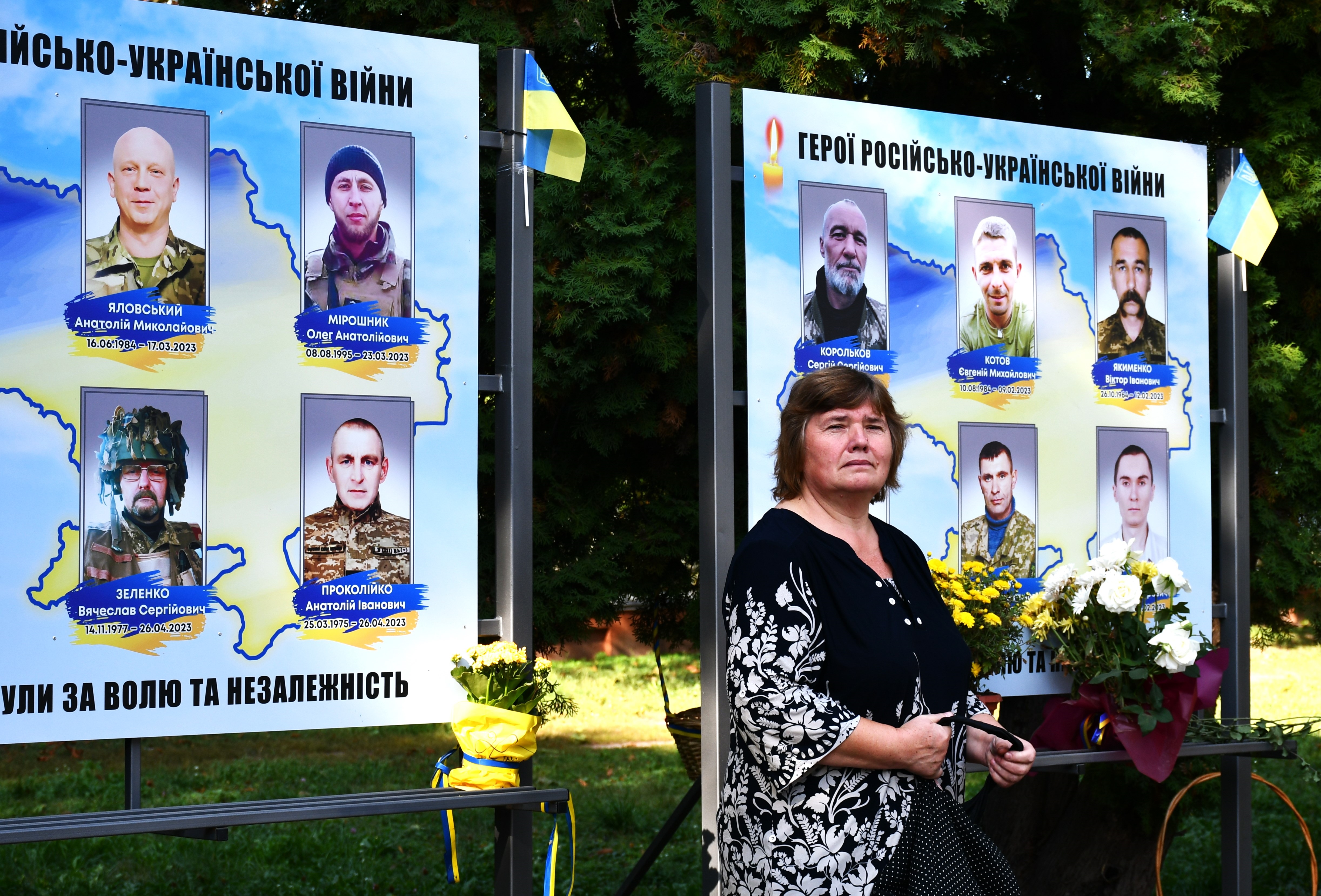 Eine Frau steht vor Bildern gefallener Soldaten