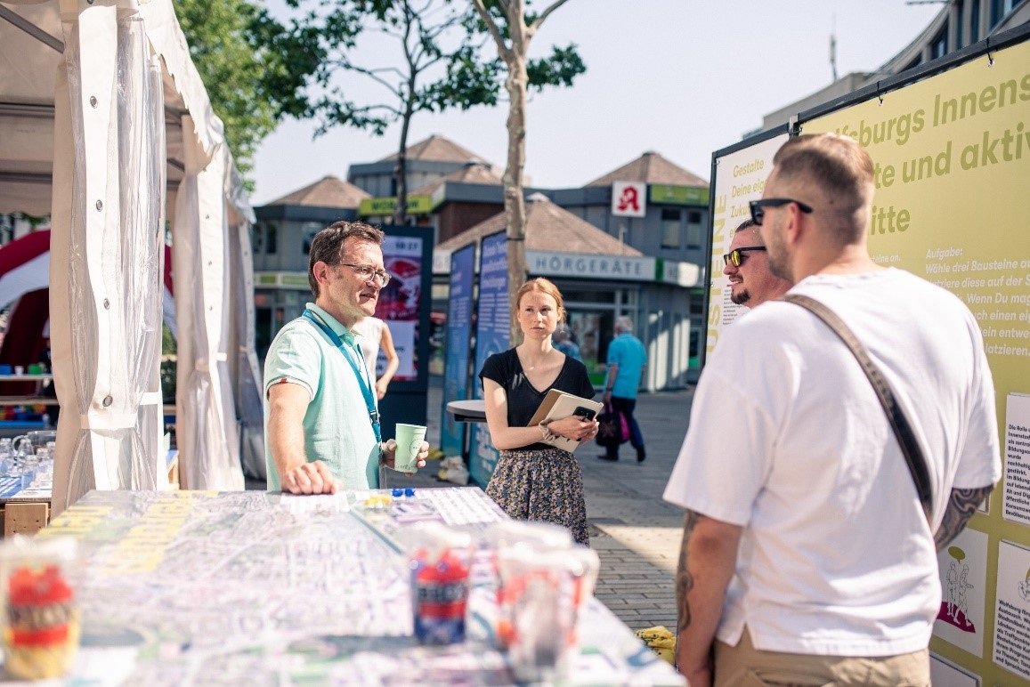 Menschen informieren sich an einem Stand in der Innenstadt