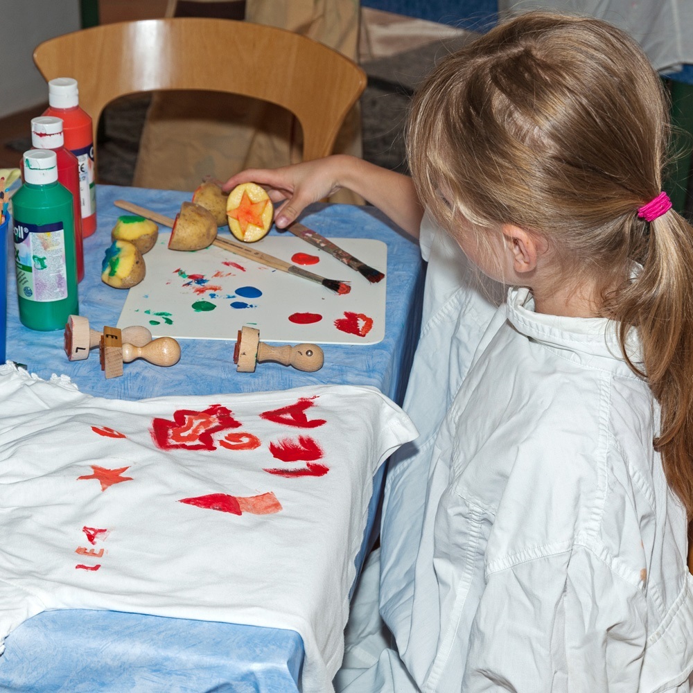Ein Kind beim Bedrucken eines T-Shirts