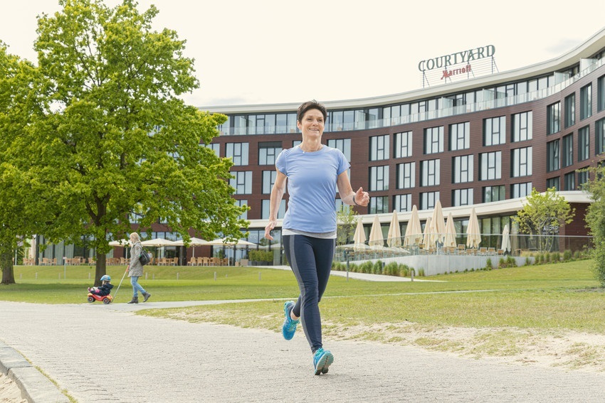 Joggerin im Allerpark mit Blick auf das Courtyard